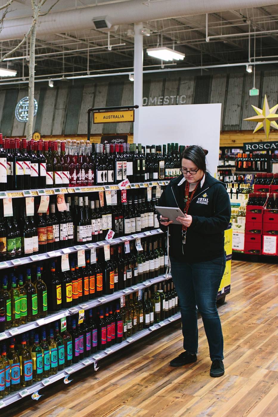 A store team member checking inventory in the wine aisle of a real mPower customer store